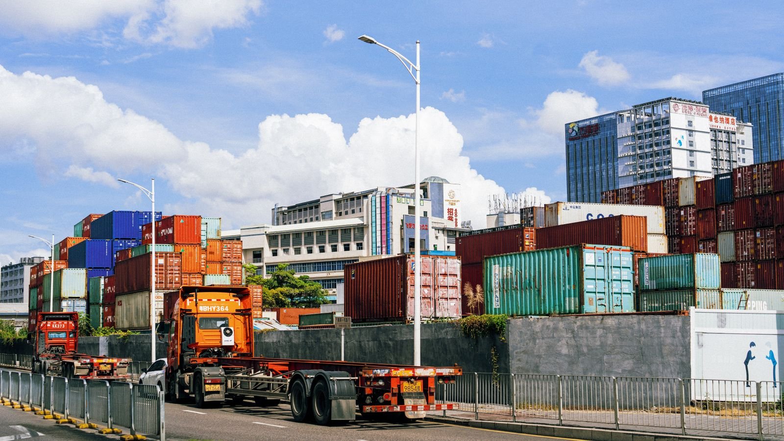 HGV hauling a shipping container past a port container yard